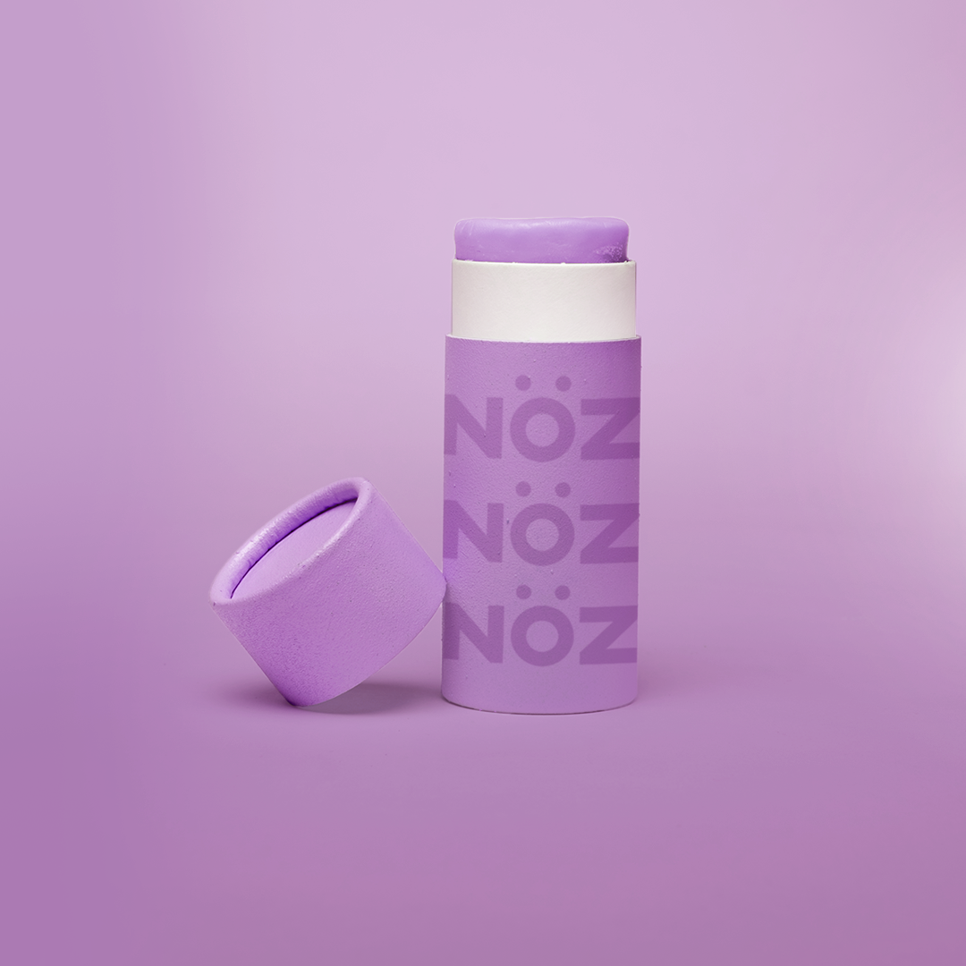 front view of purple Noz product with the cap off and leaning on the product, fun colorful sunblock stick is showing