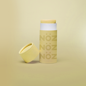 front view of yellow Noz product with the cap off and leaning on the product, fun colorful sunblock stick is showing